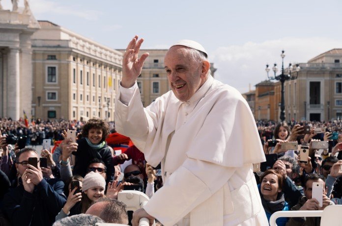 Imagem do Papa Francisco sorridente acenando para multidão de pessoas sorridentes