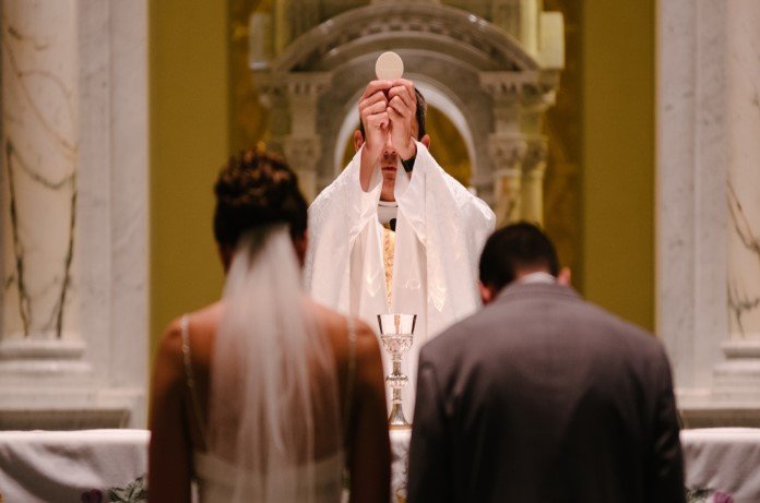 Imagem de padre no ato da consagração em um casamento na igreja