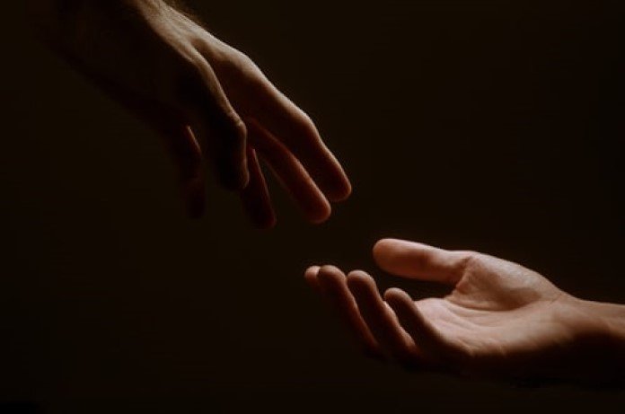 Imagem de duas mãos de duas pessoas diferentes prestes a se tocar