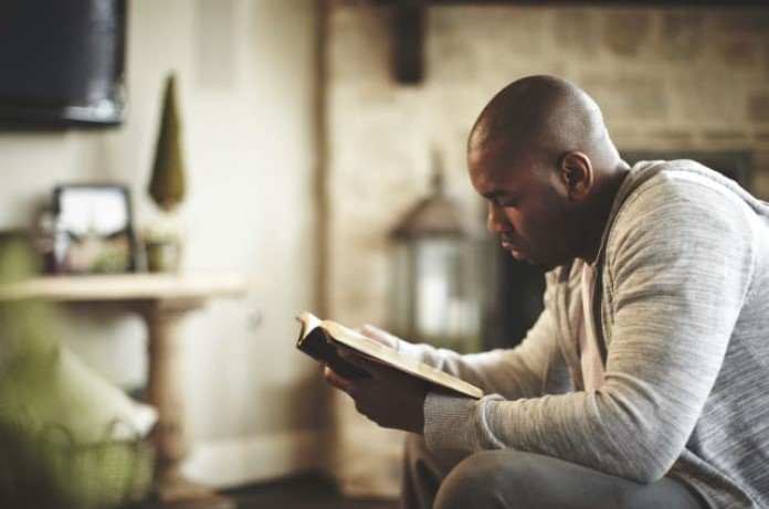 Imagem de homem lendo a bíblia na sala