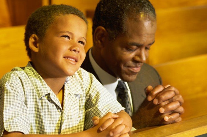 Imagem de pai e filho orando na igreja