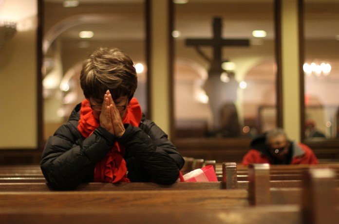 Imagem de senhora orando em uma igreja