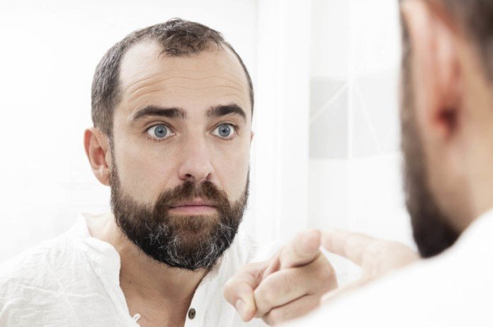 Imagem de homem apontando para o reflexo dele mesmo no espelho